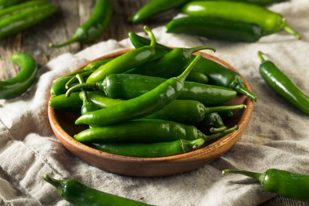 raw green organic serrano peppers in a bowl